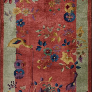 Lustrous red rug with a wide green border, detailed with stylized multicolored botanical and bird motifs.