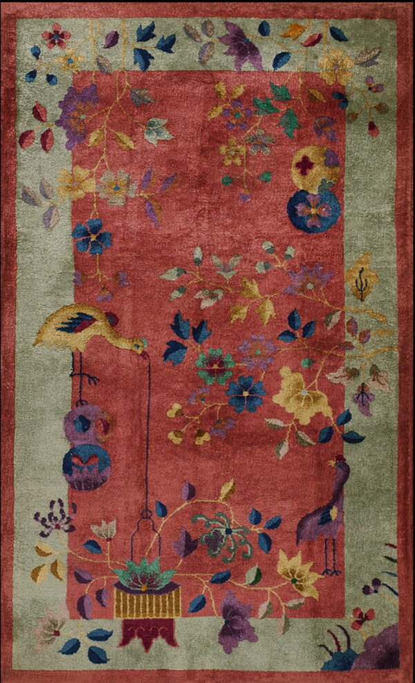 Lustrous red rug with a wide green border, detailed with stylized multicolored botanical and bird motifs.