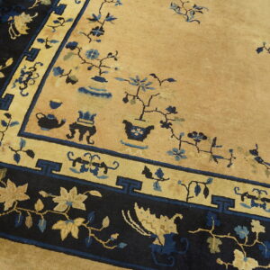 Golden tan rug with dark navy and blue borders, featuring sparse floral and vase motifs.