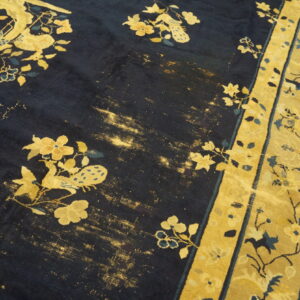 Worn dark blue rug featuring gold floral and avian designs bordered by wide yellow stripes.