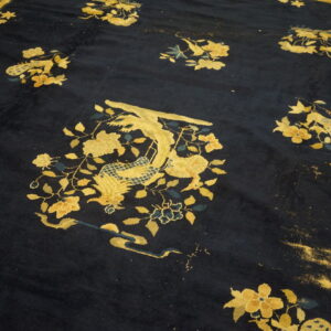Navy blue rug features scattered gold and teal mythical bird and floral designs on a heavily distressed field.