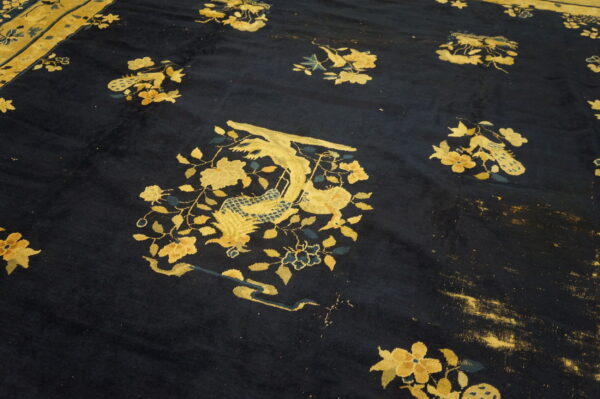 Navy blue rug features scattered gold and teal mythical bird and floral designs on a heavily distressed field.