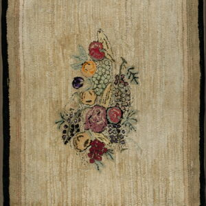 Tan textured rug featuring a dark border and a large central bouquet of brightly colored fruit and flowers.