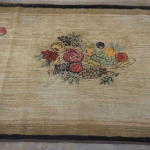 Textured beige area rug with a multicolored fruit basket center and layered brown and black borders.