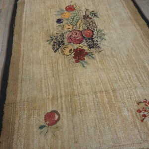 Beige textured rug with a colorful central floral and fruit motif on weathered wood planks.