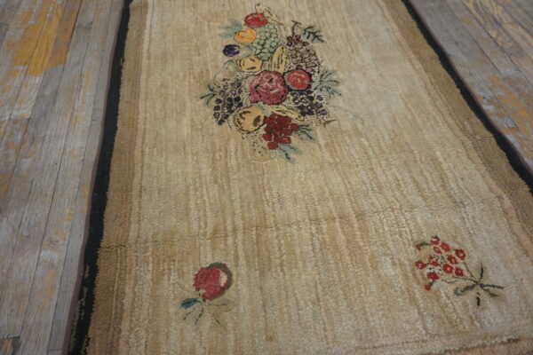 Beige textured rug with a colorful central floral and fruit motif on weathered wood planks.