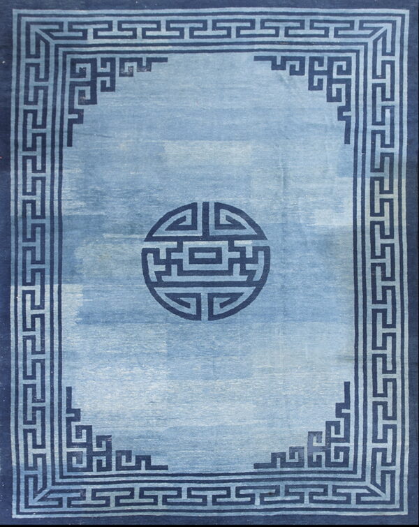 Monochromatic blue rug with a light blue field, a dark geometric border, and a circular central motif.