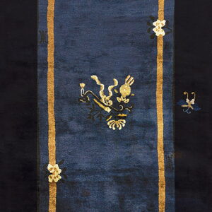 Dark blue runner rug framed by gold stripes, featuring a central gold symbol and black floral borders.