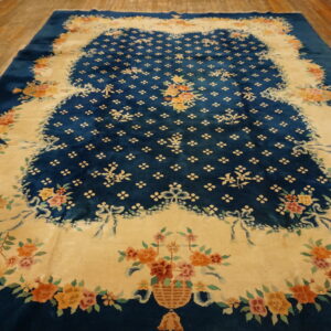 A deep blue plush rug with colorful floral bouquets and a cream-colored border resting on wood flooring.