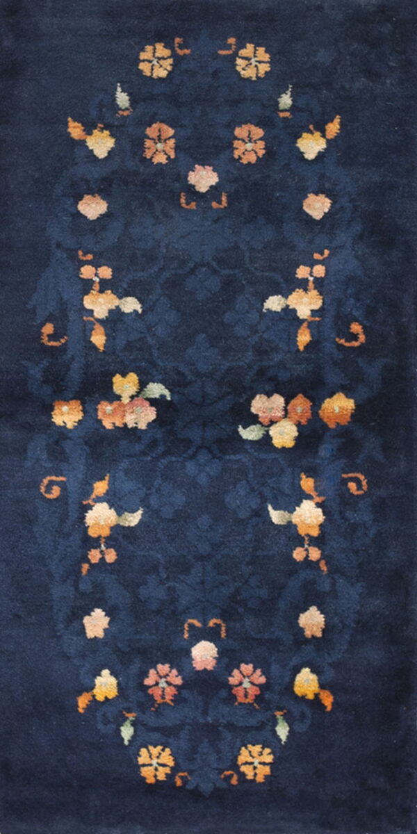 High-pile navy rug features tone-on-tone scrolling and symmetric bouquets of orange, yellow, and peach floral designs.