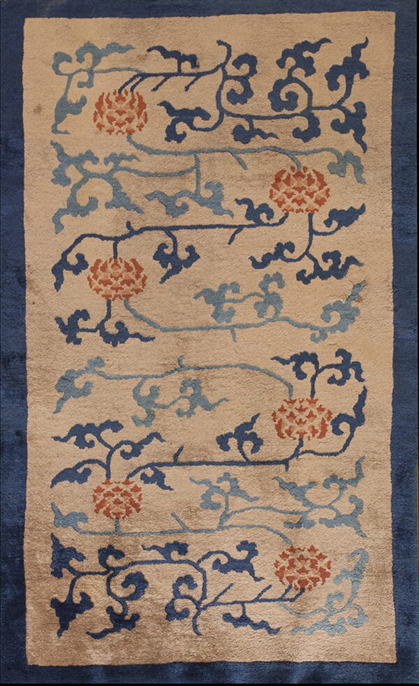 A beige rug with an indigo border and a scrolling pattern of rust florals and blue clouds.