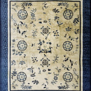 Beige area rug featuring scattered dark blue botanical designs and a wide, geometric Greek key border.