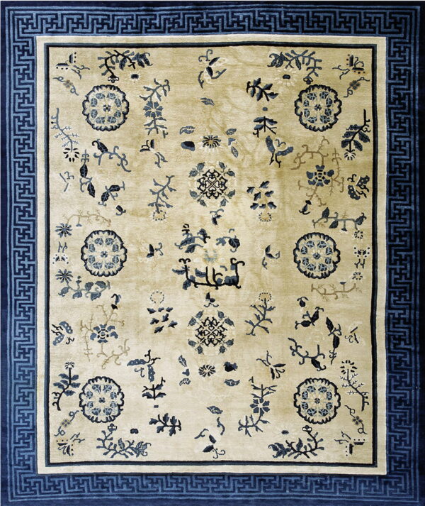 Beige area rug featuring scattered dark blue botanical designs and a wide, geometric greek key border.