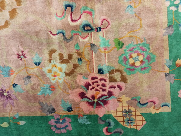 Plush pink rug with stylized colorful flowers and leaves, framed by a bright green border.