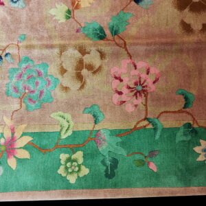 The rug displays stylized pink and teal floral vines against a mottled blush and tan field.