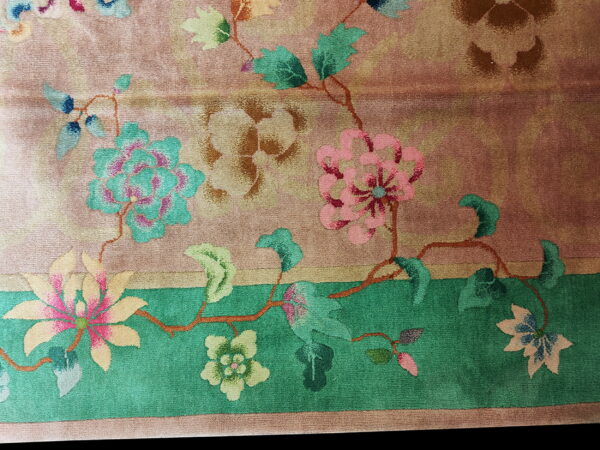 The rug displays stylized pink and teal floral vines against a mottled blush and tan field.