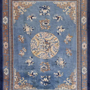 Blue traditional rug with a central medallion and scattered florals in tan, cream, and dark blue.