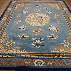 Blue rug with cream, navy, and tan floral and geometric patterns, displayed on hardwood flooring.