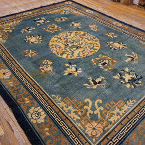 Teal and gold rug with a complex floral medallion and geometric borders on distressed wood floor.