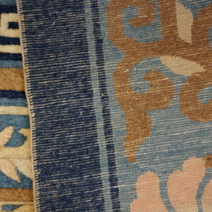 Detail of two rugs; one plush blue/tan geometric pattern and one striped flatweave with large floral motifs.