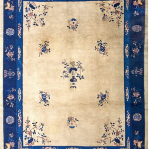 Beige rug with a dark blue border, featuring scattered floral and vase motifs in the center field.