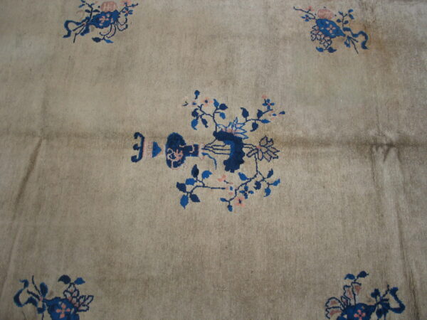 Low-pile rug in dusty beige with stylized blue and pink floral patterns.