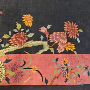Plush rug detail showing stylized multicolored floral motifs on a dark field and wide dusty rose border.