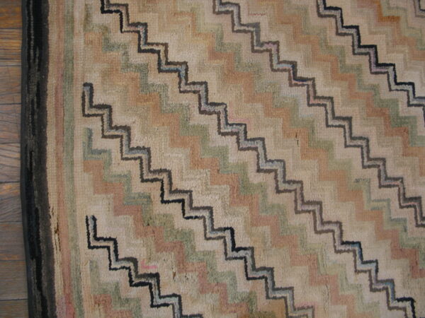 A textured, colorful rug featuring large diagonal stepped zig-zags rests on wood plank flooring.