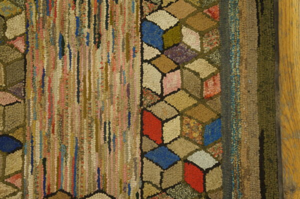A multicolor, highly textured rug featuring vertical rag strips and an elaborate tumbling block border design.