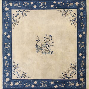 Square rug with a beige field and wide navy blue border featuring floral and traditional motifs.