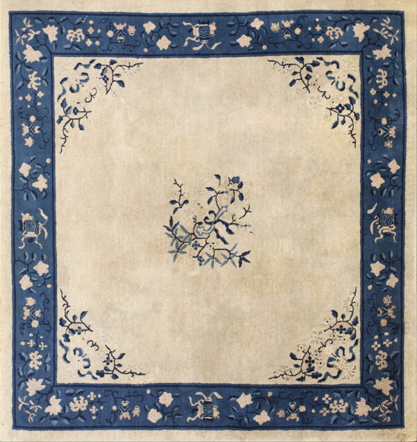 Square rug with a beige field and wide navy blue border featuring floral and traditional motifs.