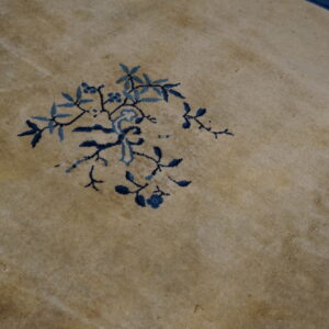 Close detail of a soft beige rug with an intricate two-tone blue floral branch design.