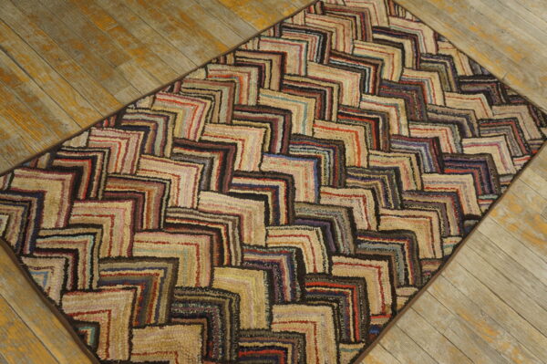 Textured multicolored rug with an interlocking log cabin pattern rests on weathered wood planks.