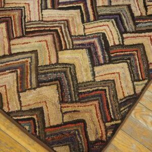 Multi-colored, textured rug with interlocking maze patterns rests on distressed yellow wooden floors.