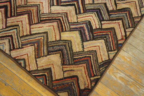 Multi-colored, textured rug with interlocking maze patterns rests on distressed yellow wooden floors.