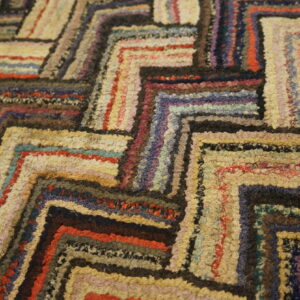 Varied-pile rug with a multicolored geometric pattern in patches of cream, brown, red, blue, and purple.