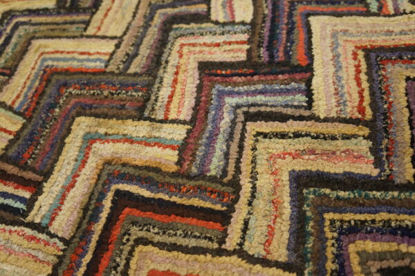 Varied-pile rug with a multicolored geometric pattern in patches of cream, brown, red, blue, and purple.