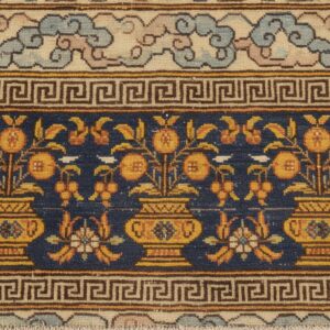 Detail of a dark blue field rug border showing repeating yellow pomegranate motifs in vases above a greek key band – by rugs on net