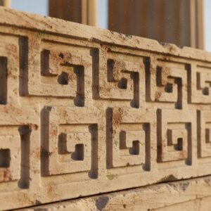 Close-up of weathered stone block featuring a deeply carved, repeating greek key pattern – by rugs on net