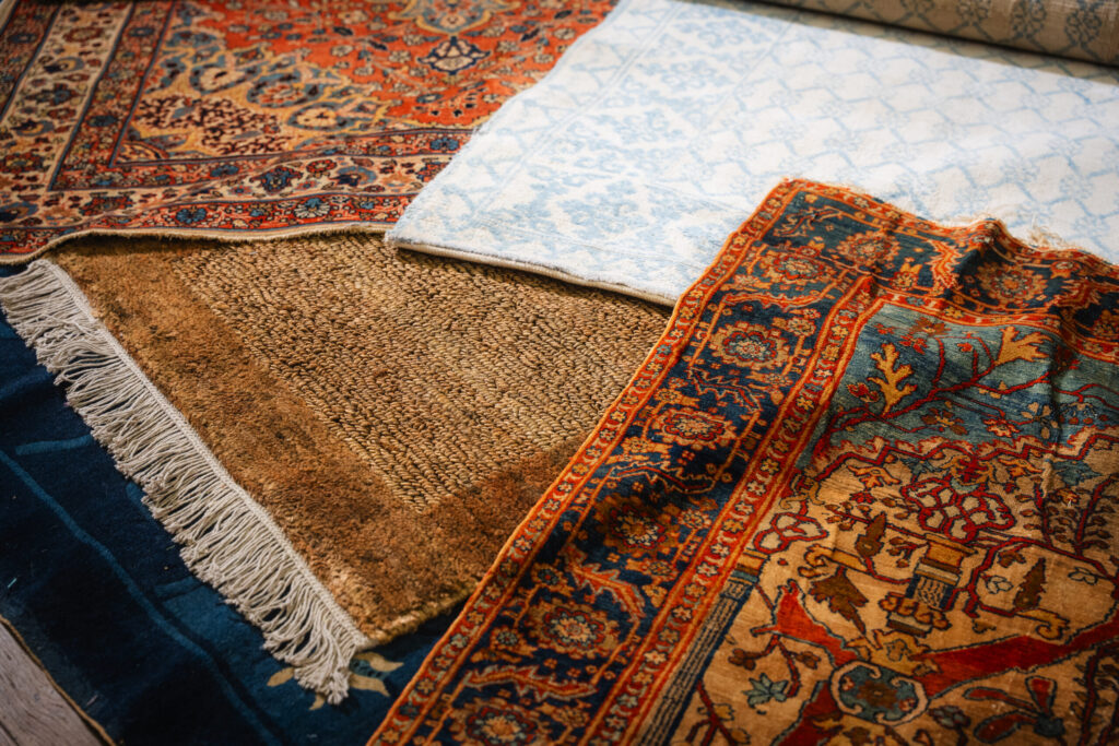 assorted handmade rugs laid out together showing different colors, patterns, and textures