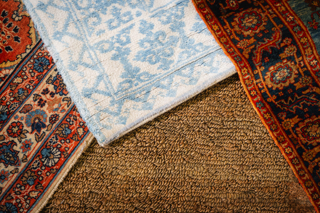 Overlapping handmade rugs showing different colors, textures, and weaving styles