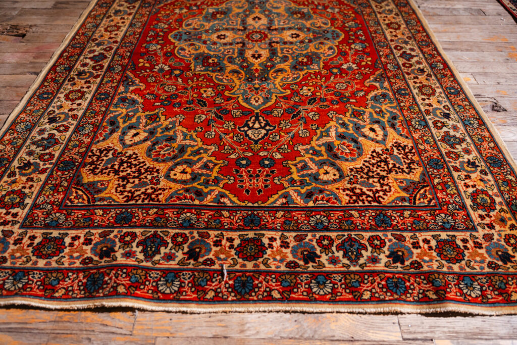 Multicolor antique Persian Tabriz rug laid down on showroom floor of Rugs On Net