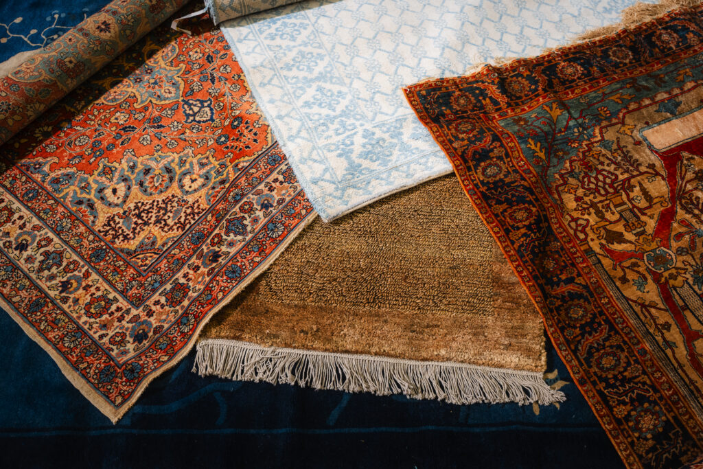 Rug buying guide - multiple handmade rugs layered together showing different patterns, colors, and textures
