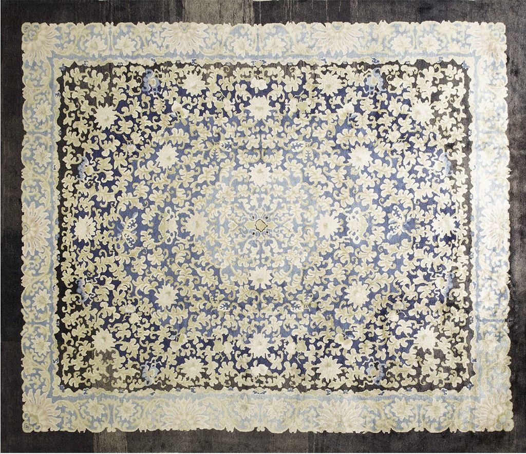 Overhead view of a rectangular, antique chinese-style rug featuring dense ivory and pale green floral patterns on a fading indigo blue field, framed by a light blue scalloped border by rugs on net.