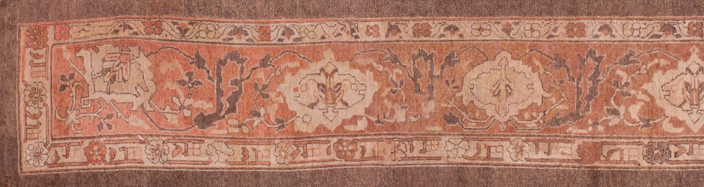 Close-up view of an antique agra hallway runner rug with faded coral, beige, and dark brown wool showing stylized floral and animal motifs along its central border by rugs on net.