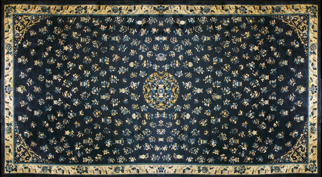 An oversized, rectangular antique chinese wool rug with a dark blue field scattered with small blue and ivory floral motifs, centered by a circular medallion, and framed by a light cream border by rugs on net.