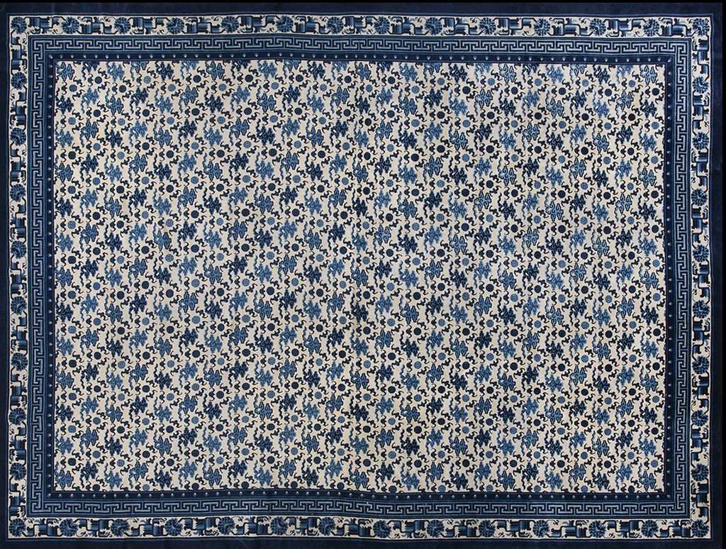 A rectangular antique peking wool rug with an all-over repeating pattern of small blue motifs on a cream background, framed by a wide, deep blue border with greek key designs by rugs on net.