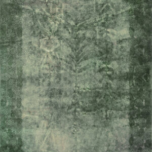 Distressed green rug with a faded floral border surrounding a lighter central field of subtle pattern.