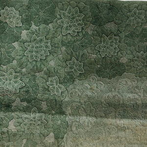 Faded, high-low pile rug texture showing an ornate floral damask pattern in muted gray and sage.