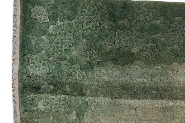 Faded, high-low pile rug texture showing an ornate floral damask pattern in muted gray and sage.